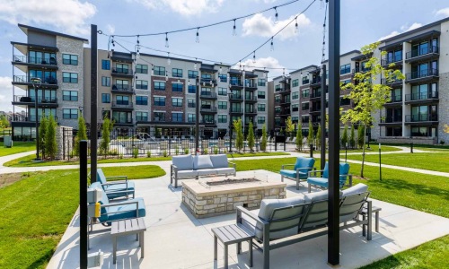 An outdoor lounge with a fire pit, couches and chairs at Reflections luxury apartments in Kansas.
